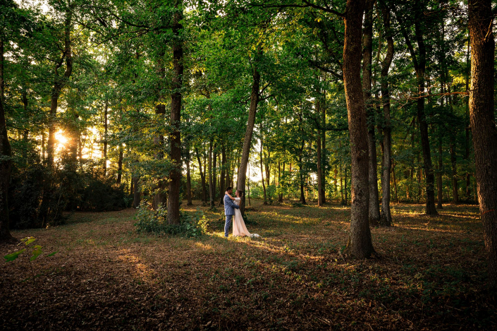 EN-407 photo d'un couple de mariés au coucher de soleil dans une forêt. ils sont de loin et s'enlacent.