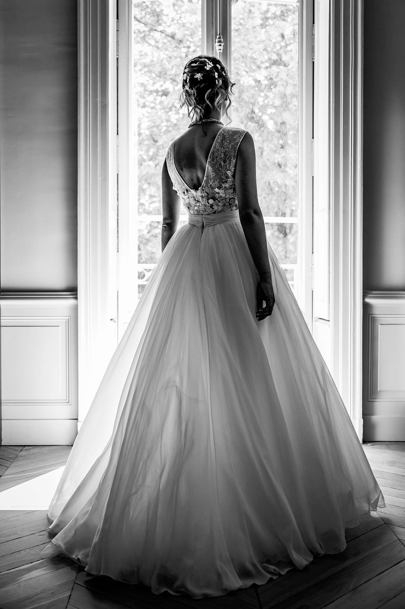 photo de mariée de dos devant une fenêtre robe de mariée en dentelle et tulle création nicolas fafiotte